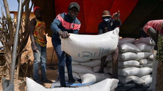 Рабочие несут помощь, предоставленную Всемирной продовольственной программой (ВПП) для распределения в Писсиле, Буркина-Фасо 24 января 2020 г.