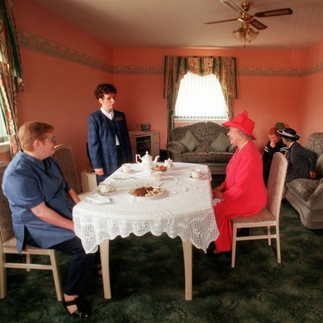 Королева присоединяется к миссис Сьюзен МакКаррон (слева на первом плане) к своему десятилетнему сыну Джеймсу и управляющему жилищным сектором Лиз МакГиннисс за чаем в их доме в Глазго, в районе Каслмилк