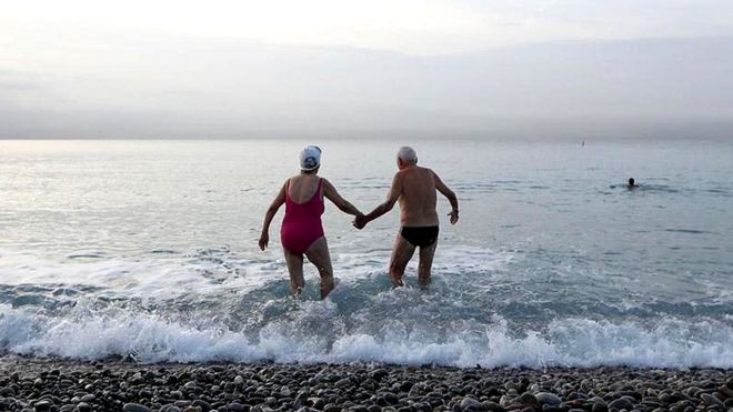 Пожилые мужчина и женщина входят в море