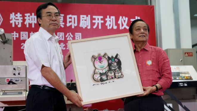 Designer Han Meilin (R) poses for pictures as he presents his design manuscript for a Year of the Pig stamp that shows a five-member pig family to Liu Aili, president of China Post, at a ceremony in Beijing, China 6 August 2018