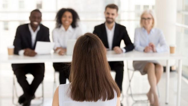 امرأة تجلس أمام هيئة تحكيم -من أصدقاء يتظاهرون بأنهم مديرين موارد بشرية- من أجل مقابلة شخصية للحصول على وظيفة