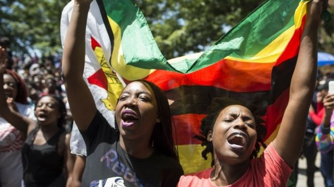 Женщины с флагом Зимбабве принимают участие в демонстрации студентов Университета Зимбабве, которая состоится 20 ноября 2017 года в Хараре