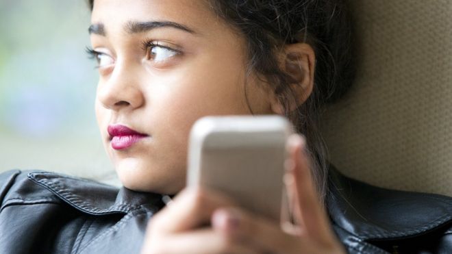 Young girl early teens playing on her phone and texting