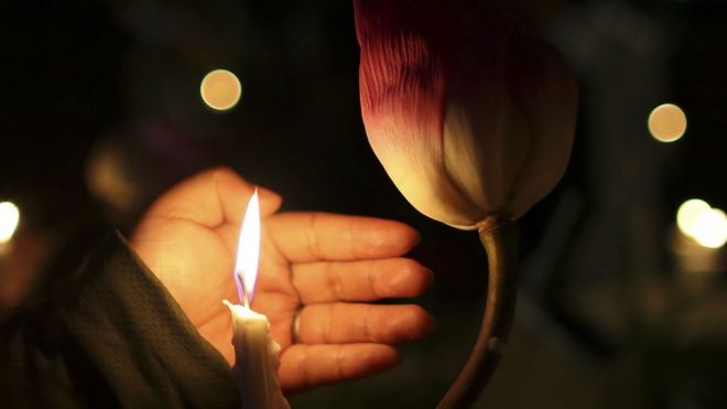 Женщина держит свечу во время бдения при свечах, отдавая дань памяти жертвам взрывов на Шри-Ланке