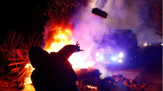 Protester throws a stone at a bus of evacuees from China in Novi Sanzhary, in Ukraine's central Poltava region