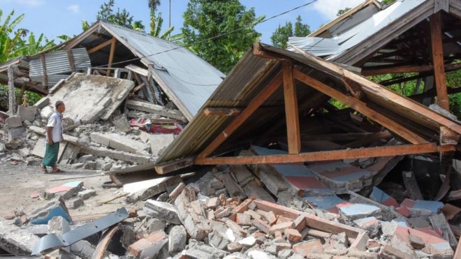 Индонезийский мужчина осматривает остатки домов после землетрясения силой 6,4 балла в Ломбоке 29 июля 2018 года