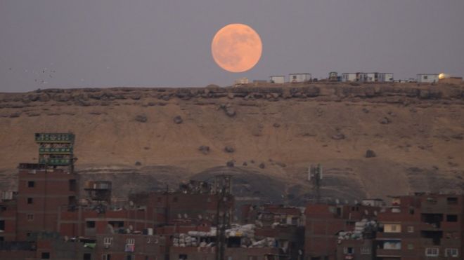 На снимке, присланном Эмадом Каримом в Каир, Египет, светящаяся оранжевая луна над красноватыми египетскими песками