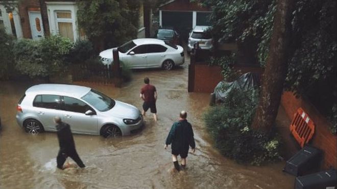 Мужчины пробираются через воду возле своих домов