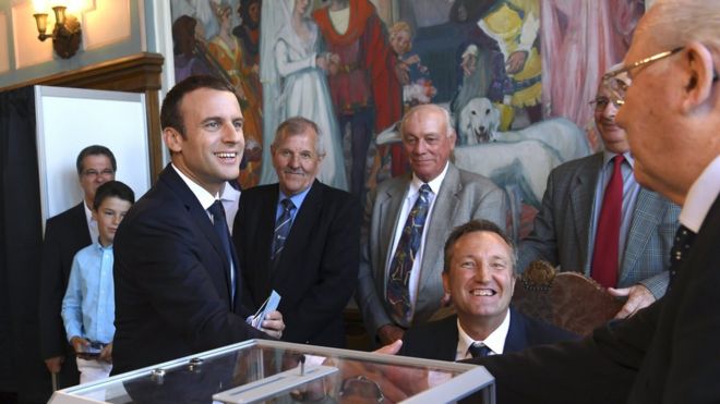Президент Франции Эммануэль Макрон (слева) обменивается рукопожатием с голосующим чиновником после голосования во втором туре выборов в законодательные органы Франции в мэрии в Ле-Туке, Франция, 18 июня 2017 года.