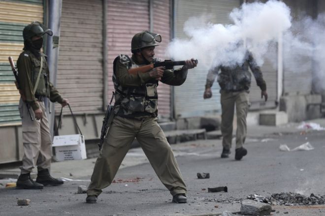 Индийский военизированный солдат стреляет слезоточивым газом в протестующих