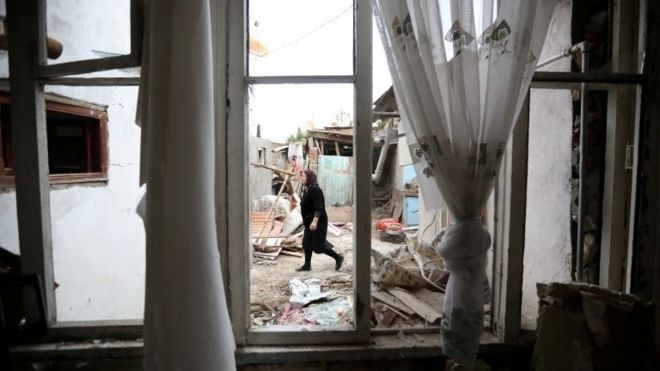 Woman walks past house damaged by shelling in the Azerbaijani city of Ganja - 6 October