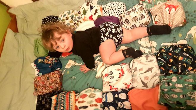 Малыш на кровати в окружении подгузников