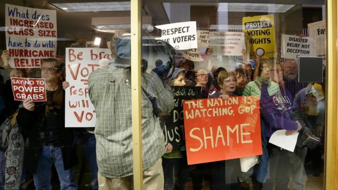 Протестующие собираются возле зала для пресс-конференций во время специальной сессии в Законодательном собрании Северной Каролины в Роли, Северная Каролина, четверг, 15 декабря 2016 года.