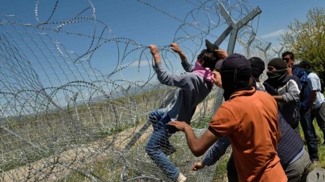 Migrants try to break a fence at the Greece-Macedonia border, 16 April