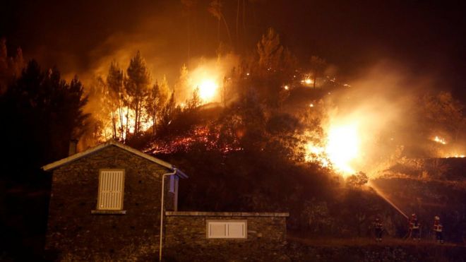 Пожарные работают, чтобы спасти дом от лесного пожара в Карвалью, недалеко от Гойса, Португалия, 19 июня 2017 г.