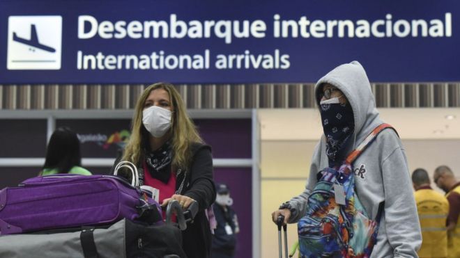 Dos personas con mascarillas en un aeropuerto de Brasil.