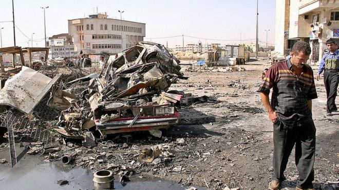 Иракское гражданское лицо осматривает ущерб в полицейском участке, который был уничтожен в результате взрыва автомобиля-смертника в Мосуле (26 июня 2005 года)
