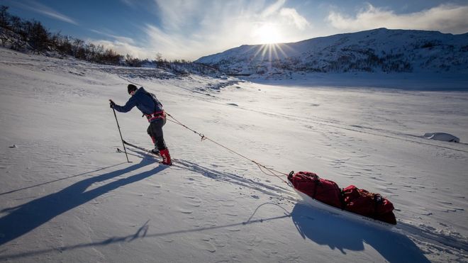 Баз Грей тянет свои санки на холм в Антарктике
