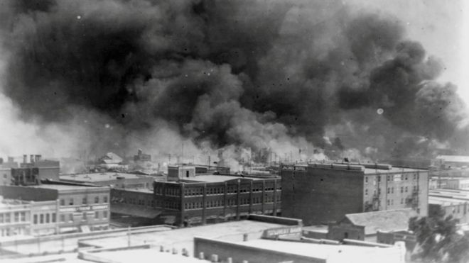 Дым поднимается от зданий во время беспорядков на гонках в Талсе, штат Оклахома, США, в 1921 году