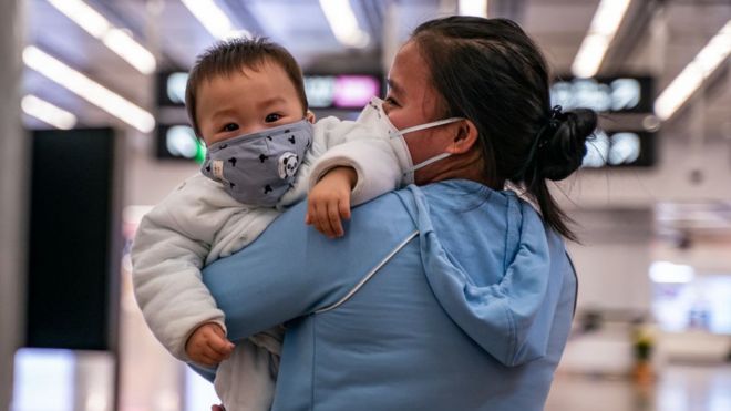 Una mujer sosteniendo a un bebé con una máscara protectora en Hong Kong.