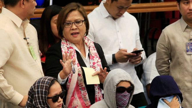 Сенатор Лейла Де Лима, председатель Комитета по справедливости и правам человека, показывает, как она стоит рядом с родственниками убитых людей во время слушаний в Сенате по расследованию убийств, связанных с наркотиками, в штаб-квартире Сената в городе Пасай, в метро Манила