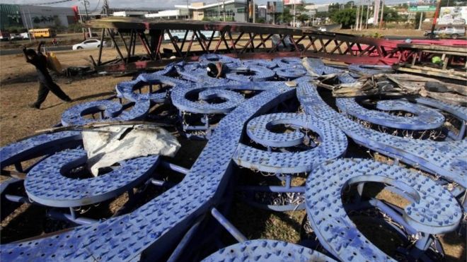 Мужчины срезают кабели и металлические детали для продажи на рынке из стального дерева правительства Никарагуа («Деревья жизни»), сгоревшего во время протеста против правительственных реформ в Институте социального обеспечения (INSS) в Манагуа 22 апреля 2018 года. || | Магазины были разграблены в Манагуа