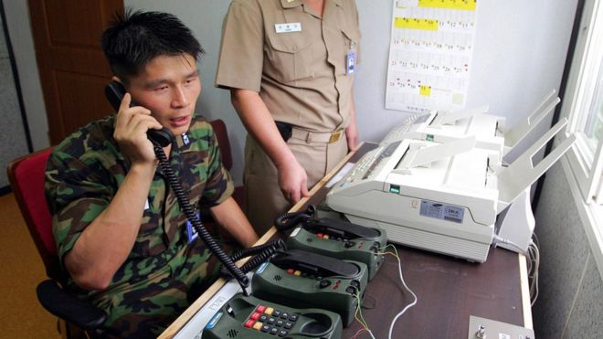 A Korean soldier on the southern side of the border speaks on a telephone, which appears to be heavy-duty and military in nature