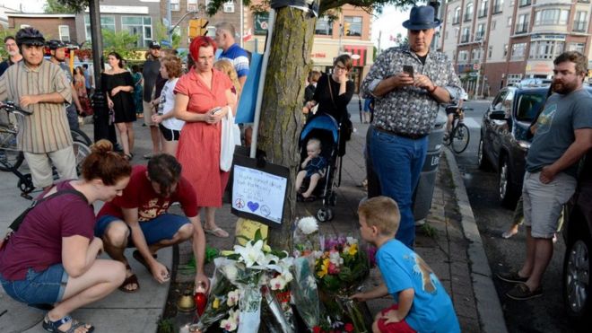 Скорбящие люди оставляют цветы у памятника жертвам массовых расстрелов на проспекте Данфорт в Торонто