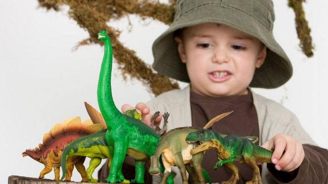 Niño jugando con dinosaurios.