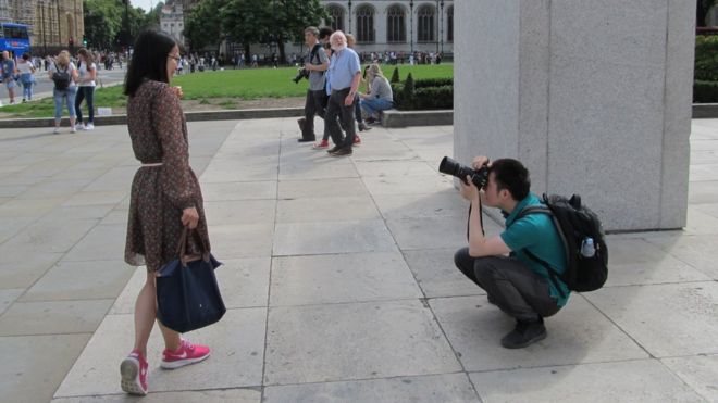 Мужчина стоит на коленях, чтобы сделать фотографию женщины