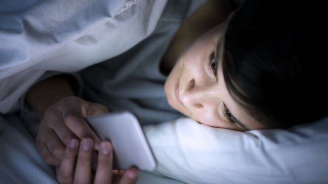 Женщина с помощью своего смартфона в постели