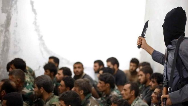 Боец Исламского государства делает жест ножом, обращаясь к захваченным сирийским солдатам после падения авиабазы ??Табка в провинции Ракка (27 августа 2014 года)