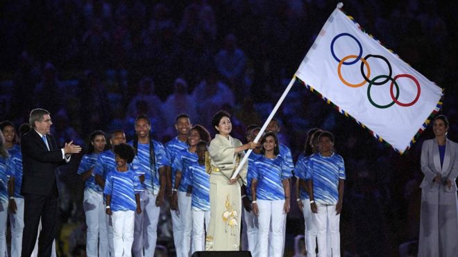 Губернатор Токио Юрико Коике (справа) развевает олимпийский флаг во время церемонии закрытия Олимпийских игр 2016 года в Рио, 21 августа 2016 года в Рио.