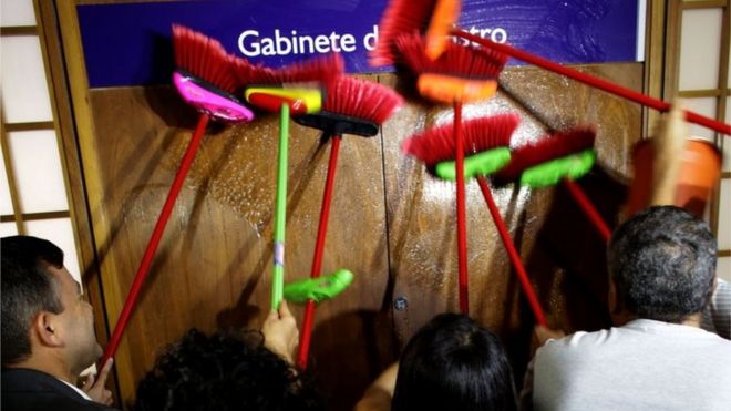 Сотрудники министерств используют метлы, чтобы стучать в дверь кабинета министра прозрачности Фабиано Сильвейры, требуя его отставки, в Бразилиа, Бразилия, понедельник, 30 мая 2016 г.