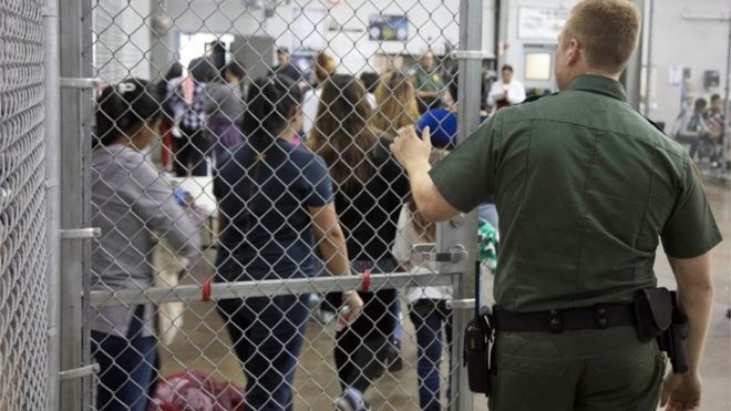 Un agente de seguridad abre la puerta de la jaula a inmigrantes detenidos.