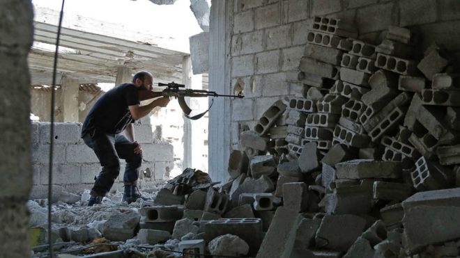 Syrian rebel fighter from the Faylaq al-Rahman brigade fires a weapon in the Eastern Ghouta area on July 17, 2017