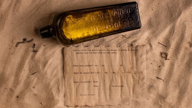 The bottle and the note placed on a sandy surface