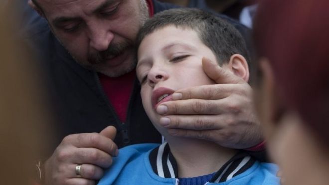 Скорбящие на похоронах в Стамбуле пытаются утешить девятилетнего Каяна, чей отец был убит в Анкаре