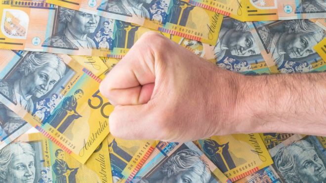 Кулак лежит на нескольких австралийских банкнотах по 50 долларов