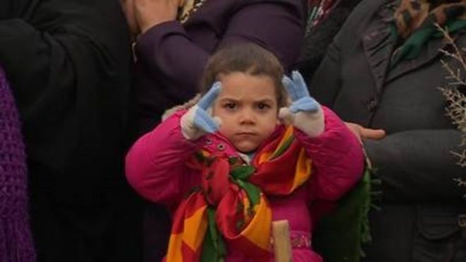 Devojčica obučena u nacionalne boje Kurda pokazuje znak za mir