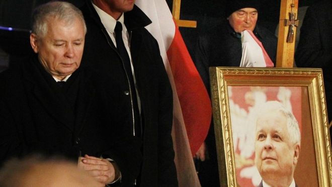 Ярослав Качиньский (слева), лидер правящей партии «Право и справедливость», принимает участие в церемонии поминовения авиакатастрофы 2010 года, в которой погибли его брат-близнец и президент Польши Лех Качиньский, увиденный справа внизу, и еще 95 человек в Смоленске