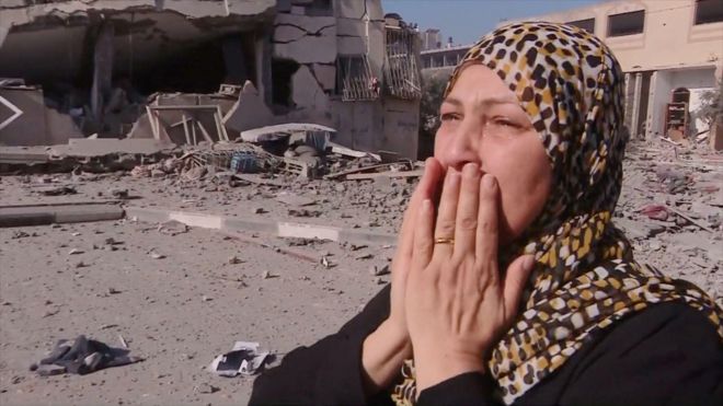 Una mujer llora ante los edificios destruidos en al Zahra
