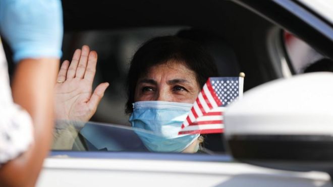 Una mujer hace el juramento en una ceremonia de naturalización en Estados Unidos desde un automóvil por motivo de la pandemia.