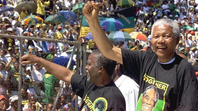 Президент Южной Африки Нельсон Мандела (справа) и заместитель президента Табо Мбеки (слева) приветствуют толпу из пикапа во время митинга Африканского национального конгресса на стадионе Орландо в Соуэто, 28 марта 1999 года.