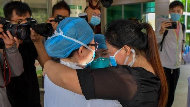 A cured COVID-19 patient embraces medical workers as she is discharged from Hainan General Hospital on March 24, 2020 in Haikou, Hainan Province of China.
