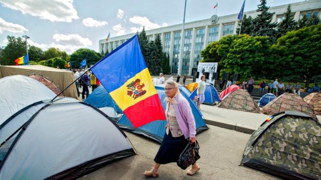 Пожилая женщина проходит палатки перед зданием правительства в Молдове