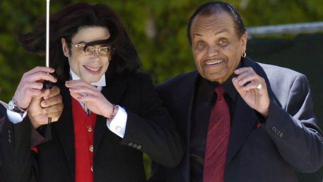 Pop star Michael Jackson and his father Joe Jackson gestures to his fans