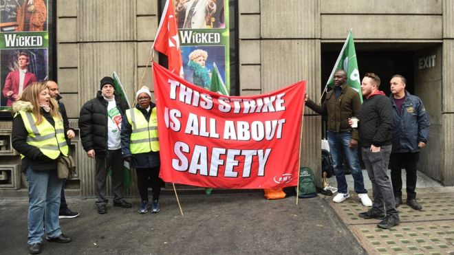Члены профсоюза стоят возле станции Виктория на линии пикета