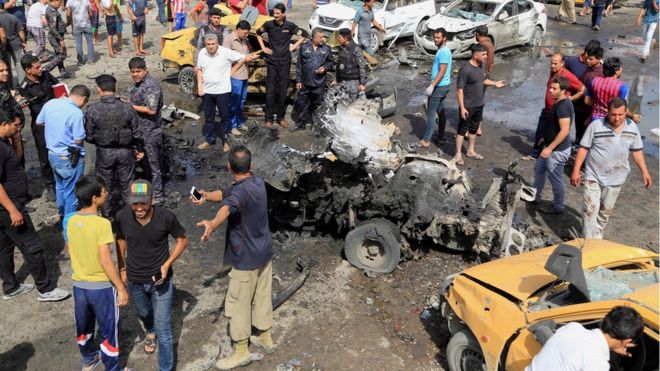 Иракские силы безопасности и люди собираются на месте взрыва автомобильной бомбы в багдадском шиитском районе города Садр