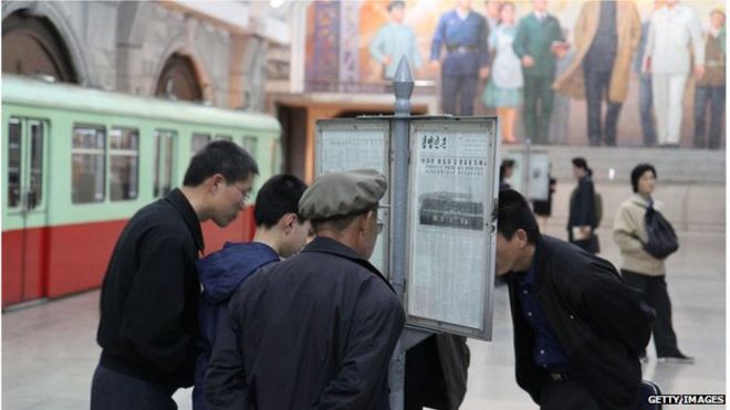 Люди читают газету в Северной Корее